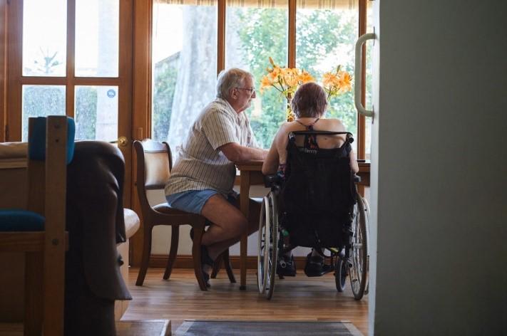 A women in a wheelchair and a man sitting at a table